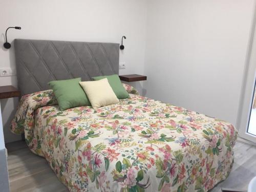 a bed with a floral comforter and two pillows at Sol de Verano in A Coruña