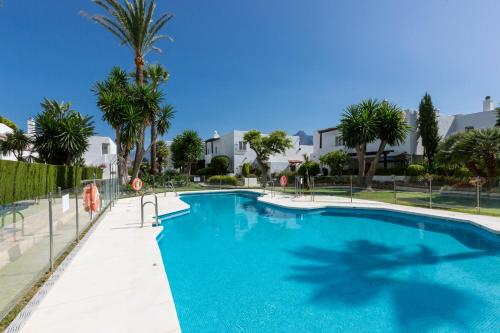 duży basen z palmami i budynkami w obiekcie Bella Vista Puerto Banus apartment with sea views w Marbelli