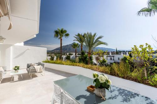 patio ze stołem, krzesłami i palmami w obiekcie Bella Vista Puerto Banus apartment with sea views w Marbelli