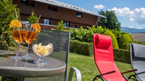 two glasses of wine on a table with a red chair at Hotel Villa Mayr Rooms & Suites in Brixen