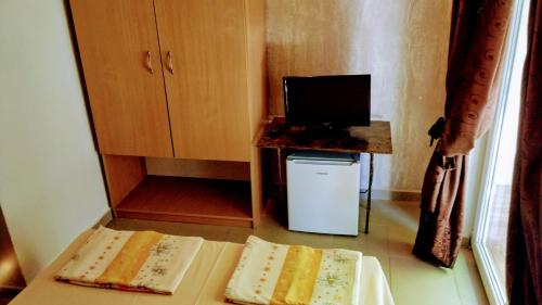 a small room with two beds and a television at Dracena Guesthouse in Ravda