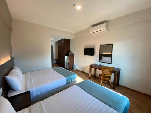 um quarto de hotel com duas camas e uma secretária em KSB Village Resort em Kampong Tambak