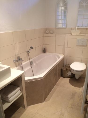 a bathroom with a tub and a toilet and a sink at Haus 8 in Lauterecken