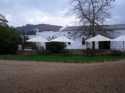 a group of tables and umbrellas in front of a building at Ongegund Lodge in Somerset West