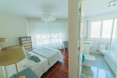 a white bedroom with a bed and a bathroom at HyP - LA CASA DE LAS HORTENSIAS in Pontevedra