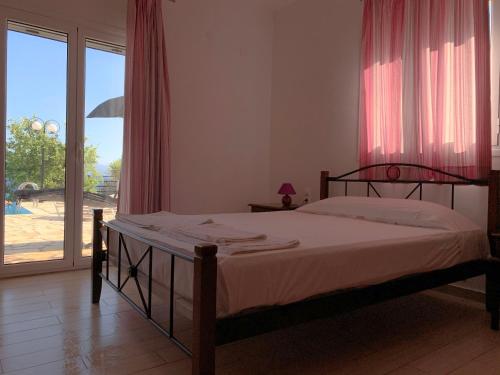 a bedroom with a bed and a large window at Aegli in Vasiliki