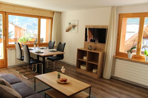 uma sala de estar com uma mesa e cadeiras e uma televisão em Haus Les Mélèzes em Zermatt