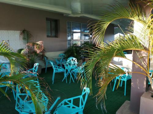 a room with blue tables and chairs and palm trees at Ayodya Suites Nyali in Nyali