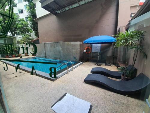 einen Pool mit einem blauen Regenschirm und einem Tisch in der Unterkunft City Plaza Nana Hotel in Bangkok