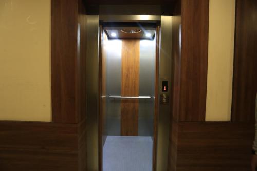 a elevator with a wooden door with a light on it at Hotel Buddha House Himalayan Brothers in Dharamshala
