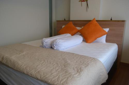 een bed met oranje en witte kussens erop bij The Cabin Apartment Uttara in Yogyakarta