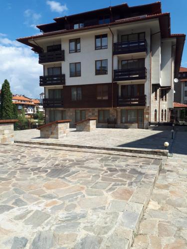 a large building with a stone courtyard in front of it at Studio in Cedar Lodge 3 in Bansko