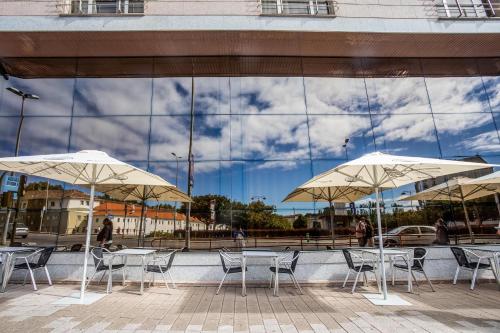 two tables and chairs with umbrellas in front of a building at Gran Hotel de Ferrol in Ferrol