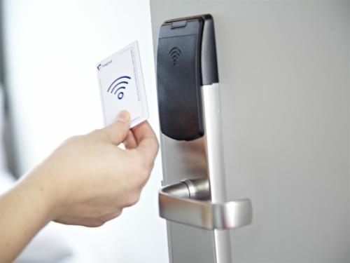 a person unlocking a door with a remote control at Road House Hotel in Paderborn