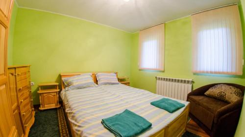a small bedroom with a bed and a chair at Къща за гости Черна река in Ribarica