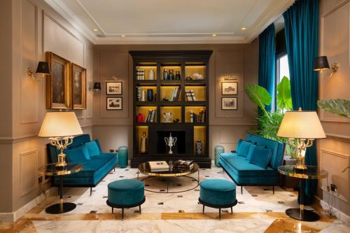 una sala de estar con sofás azules y un estante de libros. en Condotti Boutique Hotel, en Roma
