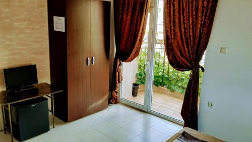 a room with a door and a window with curtains at Dracena Guesthouse in Ravda