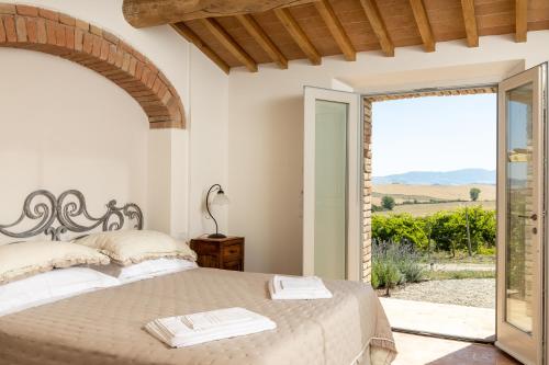 um quarto com uma cama e uma porta para um pátio em Agriturismo San Marcello em Castiglione dʼOrcia