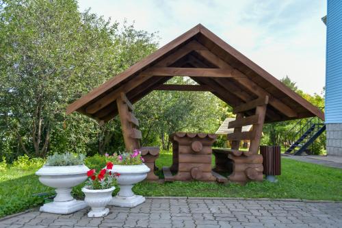 a wooden gazebo with a bench in a yard at Отель "Белокуриха" in Belokurikha