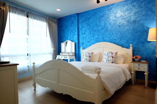 sypialnia z białym łóżkiem i niebieskimi ścianami w obiekcie Marrakesh Huahin Condo w mieście Hua Hin