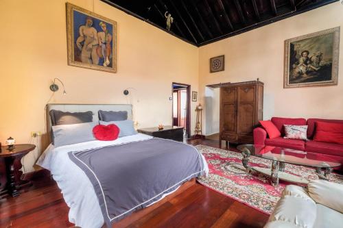 1 dormitorio con 1 cama y 1 sofá rojo en Casa Tradicional Canaria - I en Garachico