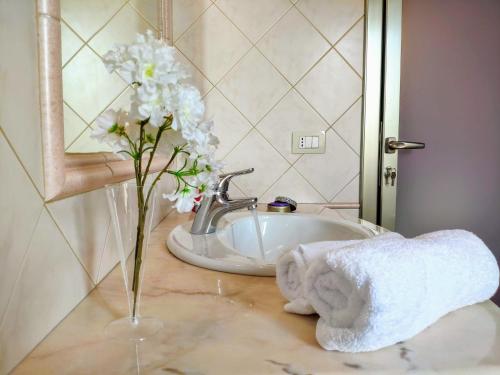 un lavandino in bagno con vaso di fiori e asciugamano di Your home in Bonaria a Cagliari