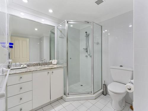 a white bathroom with a shower and a toilet at The Beach House 3BR Waterfront Apartment, Own WIFI in Trinity Beach