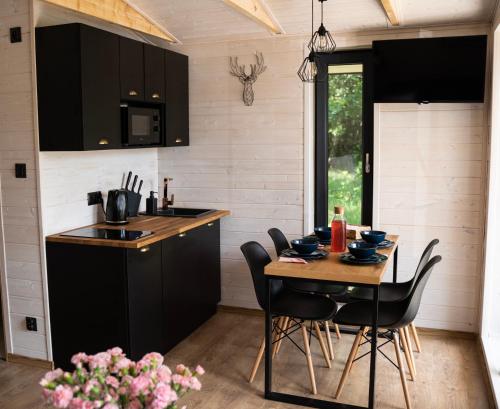 a kitchen with black cabinets and a table with chairs at Brzozowisko Tuchomko in Tuchomko
