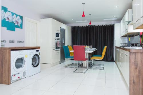 a kitchen with a washing machine and a table with chairs at Langley Guest House in Slough