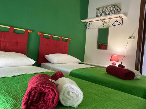 Cette chambre comprend 2 lits aux murs verts. dans l'établissement Villa Romana, à Ricadi