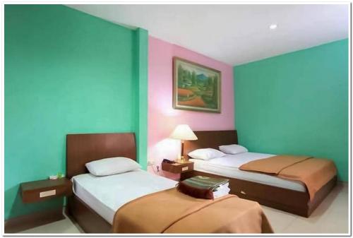 two beds in a room with blue and pink walls at The Nancy's Homestay Pekanbaru Mitra RedDoorz in Pekanbaru