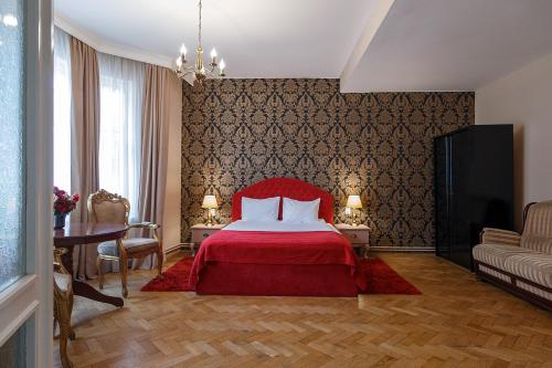 - une chambre avec un lit rouge, une table et des chaises dans l'établissement Casa Monte Verde, à Braşov