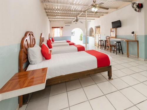 a bedroom with four beds with red pillows at Hotel Posada Agua Escondida in Cihuatlán