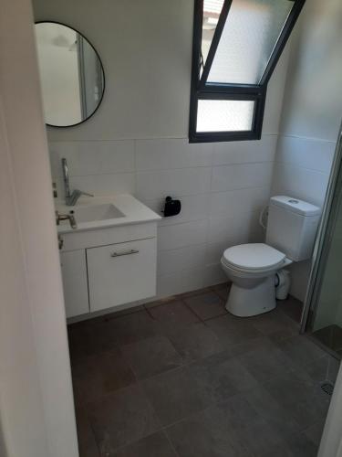 a bathroom with a toilet and a sink and a mirror at כפר הנופש מעיין in Ma‘yan Barukh