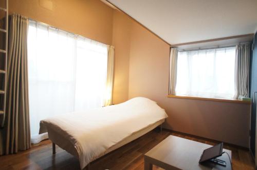 a small bedroom with a bed and a window at Plusone Nishikoen in Fukuoka