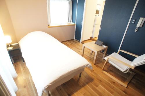 a bedroom with a bed and a chair and a window at Plusone Nishikoen in Fukuoka
