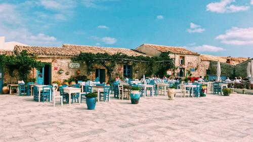 a patio with tables and chairs in front of a building at Torre Don Virgilio Country Hotel in Cannizzara