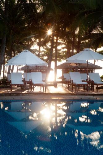 a group of chairs and umbrellas next to a swimming pool at Blue Ocean Resort in Mui Ne