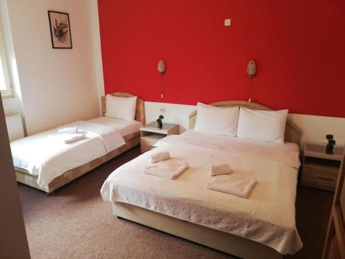 2 letti in una camera d'albergo con pareti rosse di Rooms Lisičić a Kolašin