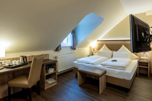 a hotel room with a bed and a desk and a tv at Hotel Ratskeller Schwarzenberg in Schwarzenberg