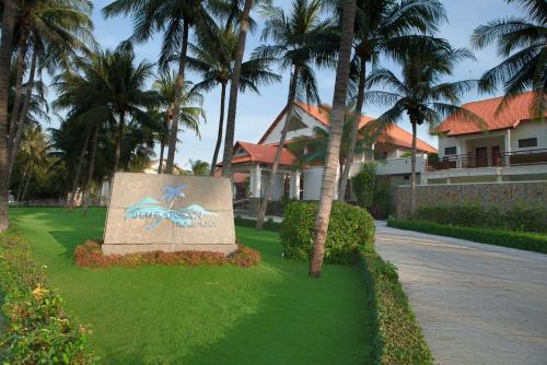 a sign in front of a house with palm trees at Blue Ocean Resort in Mui Ne