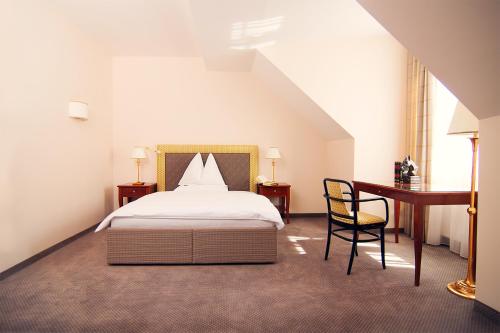 a bedroom with a bed and a desk and a chair at Parkhotel Graz - Traditional Luxury in Graz