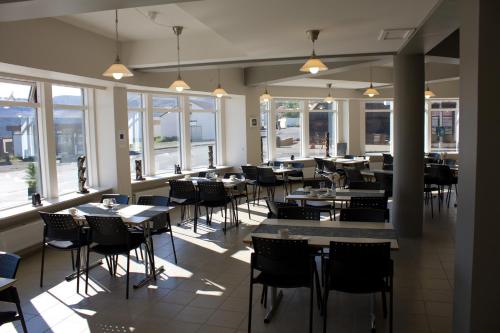 een eetkamer met tafels, stoelen en ramen bij Hótel Sandafell in Þingeyri