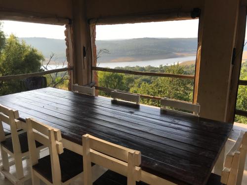 a wooden table and chairs on a balcony with a view at Fish Eagles View - on game farm close to pilansberg in Tiokweng