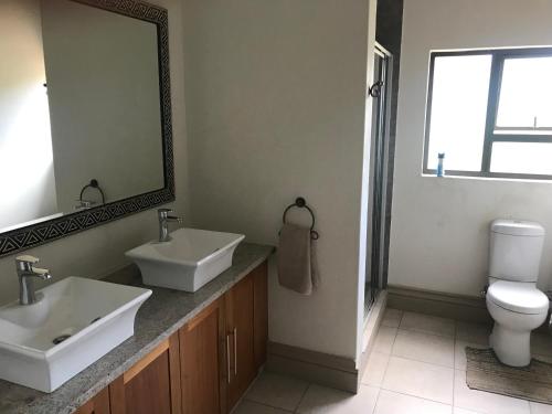 een badkamer met 2 wastafels, een toilet en een spiegel bij Fish Eagles View - on game farm close to pilansberg in Tiokweng