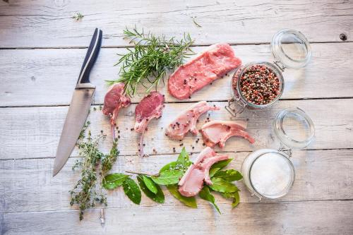 a table with meat and a knife and some herbs at Boutique Hotel Zum Rosenbaum in Nalles