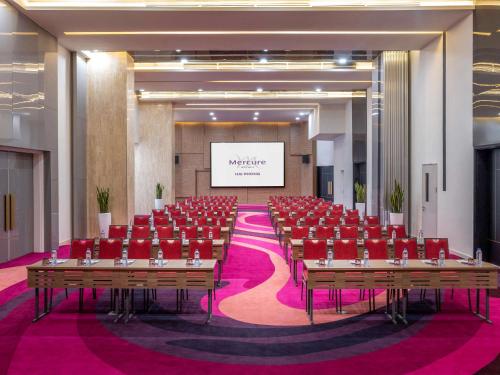 a conference room with red chairs and a projection screen at Mercure Hai Phong in Hai Phong