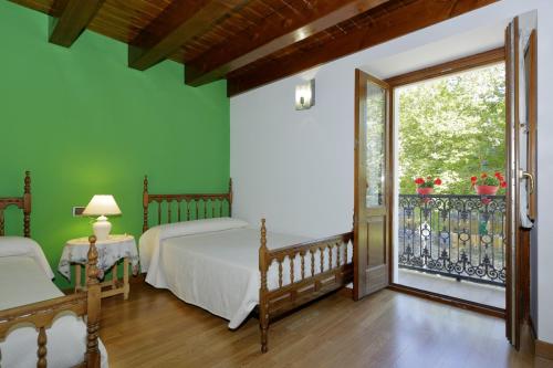 a bedroom with two beds and a balcony at Aizkolarienea in Ochagavía