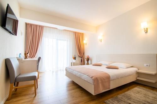 a bedroom with a large bed and a chair at Hotel Bulevard in Râmnicu Vâlcea