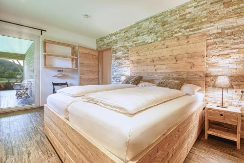 a bedroom with a large bed and a brick wall at Nockberge Lodge in Bad Kleinkirchheim
